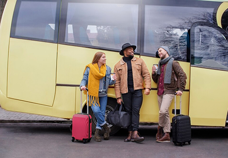 three passengers waiting next to a yellow charter bus