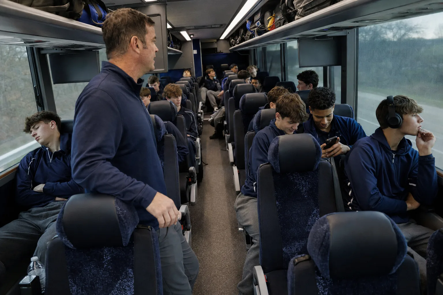 High school sports team traveling on a charter bus with reclining seats and overhead storage