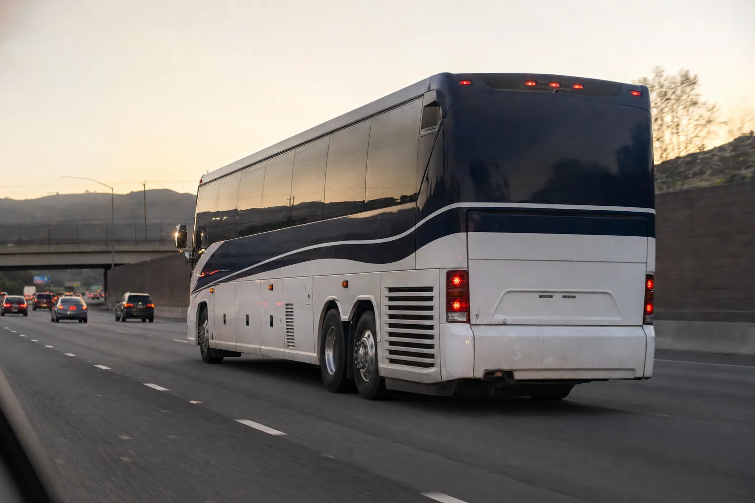Charter bus for multi-day tour travel on a Los Angeles highway at dusk