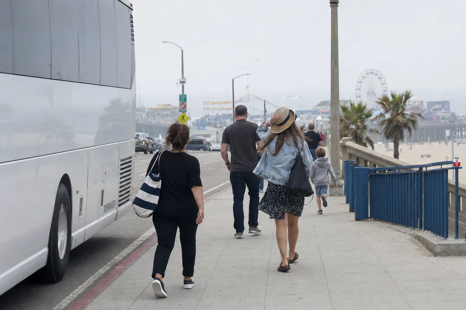 Charter bus tour group walking toward Santa Monica Pier in Los Angeles