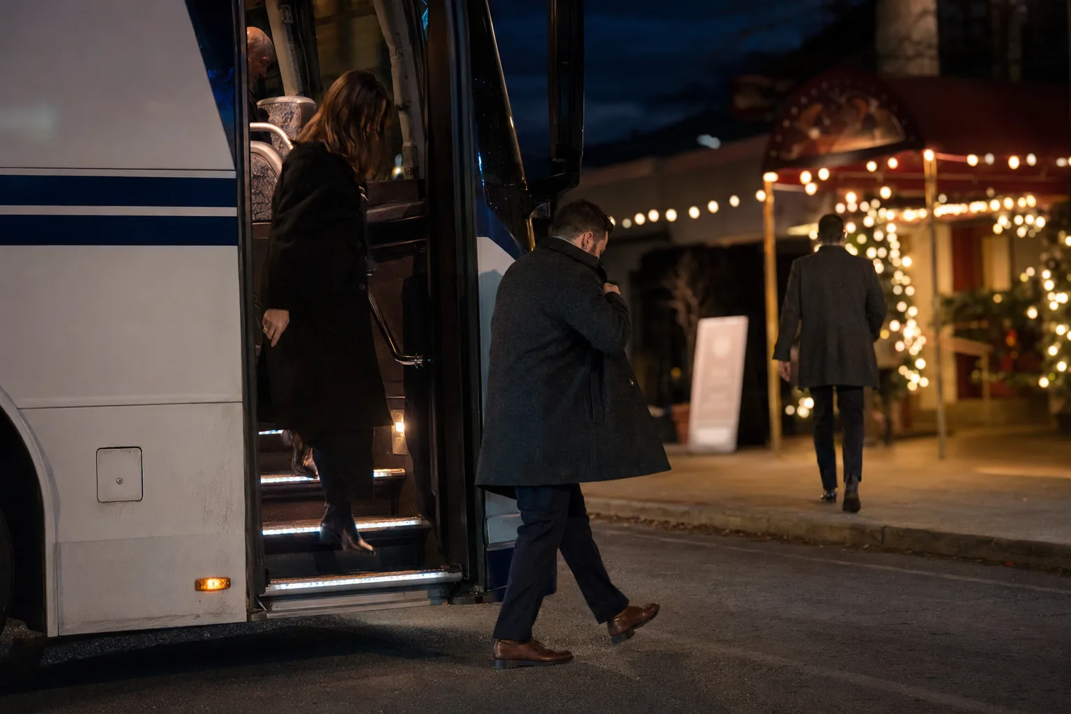 Guests arriving by charter bus at a company holiday party venue in Los Angeles at night