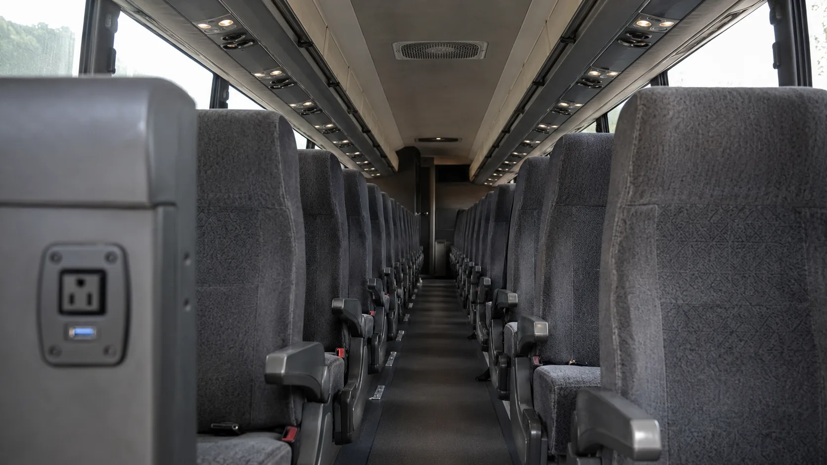 Comfortable fabric seating and power outlets inside a Los Angeles motorcoach rental